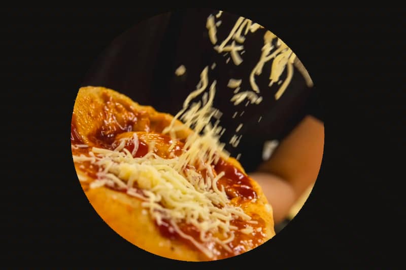 Strouhaný sýr se sype na rajčatovou omáčku na pizze