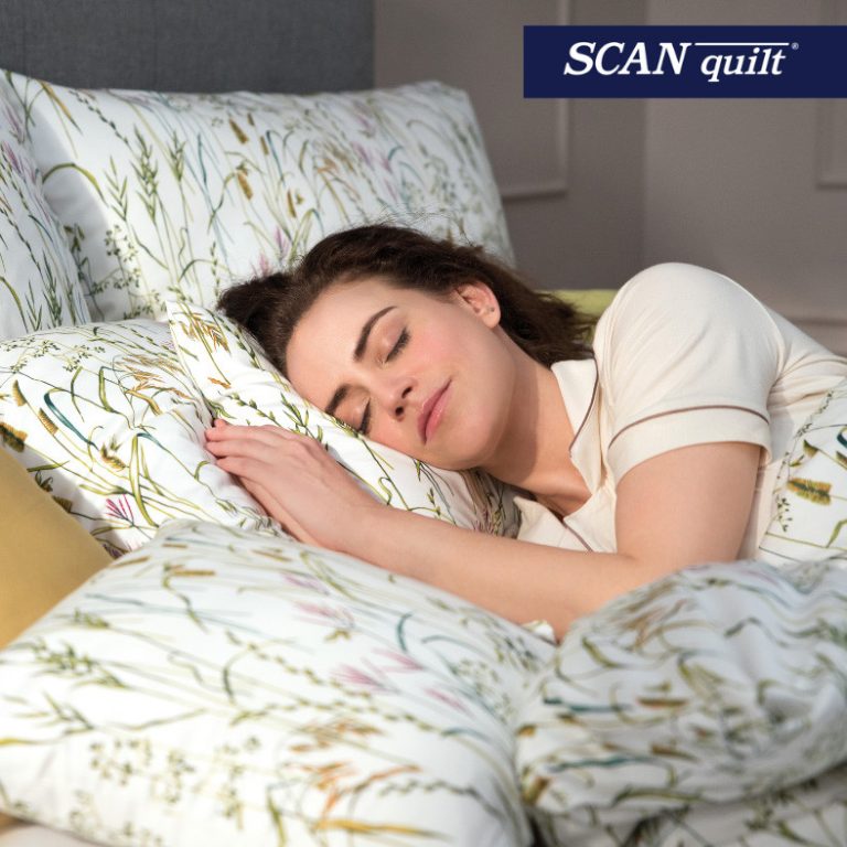 Žena spící na květinovém polštáři s logem SCAN quilt
